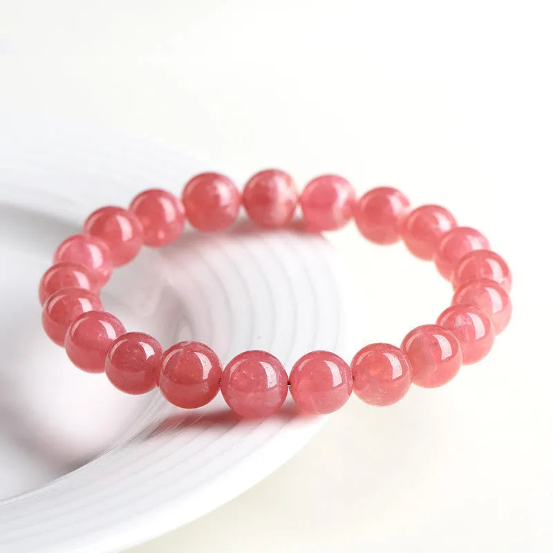 Women's red rhodochrosite crystal bracelet with geometric beads and a longevity lock clasp on a wrist.