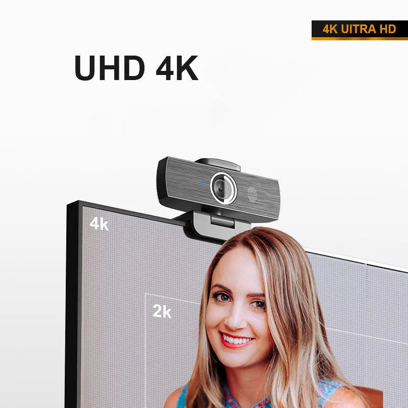 Black USB webcam with magnetic privacy cover on a desk next to a laptop.