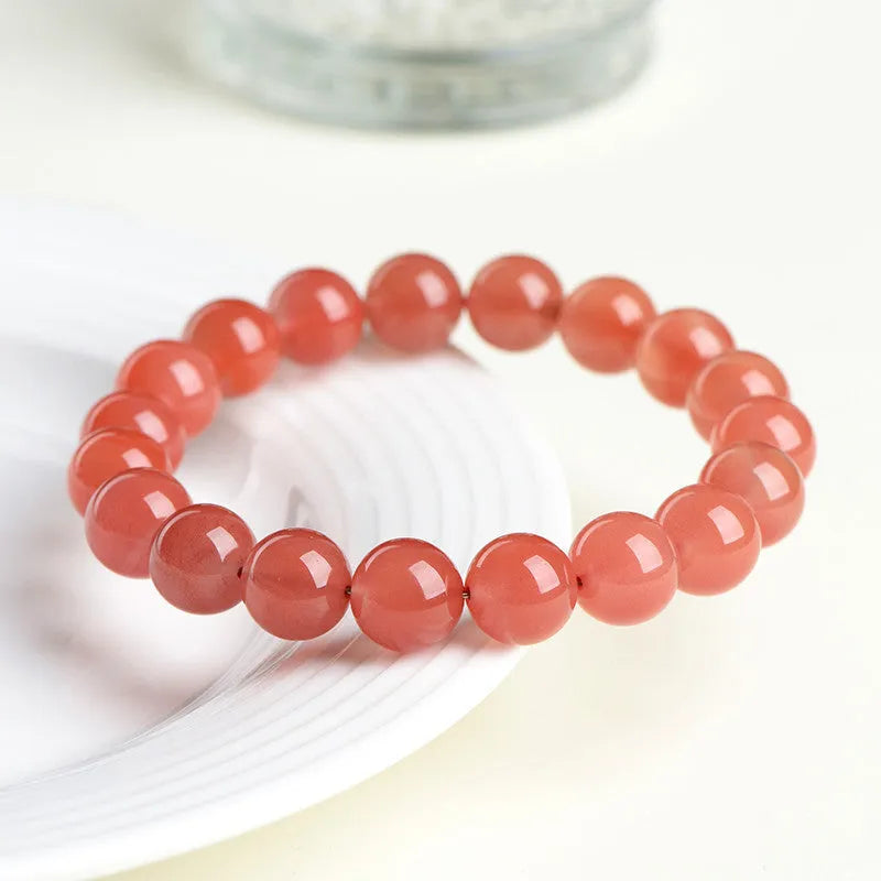 Natural South Cherry Red Agate polished bead bracelet shown in a scattered design on a wrist.