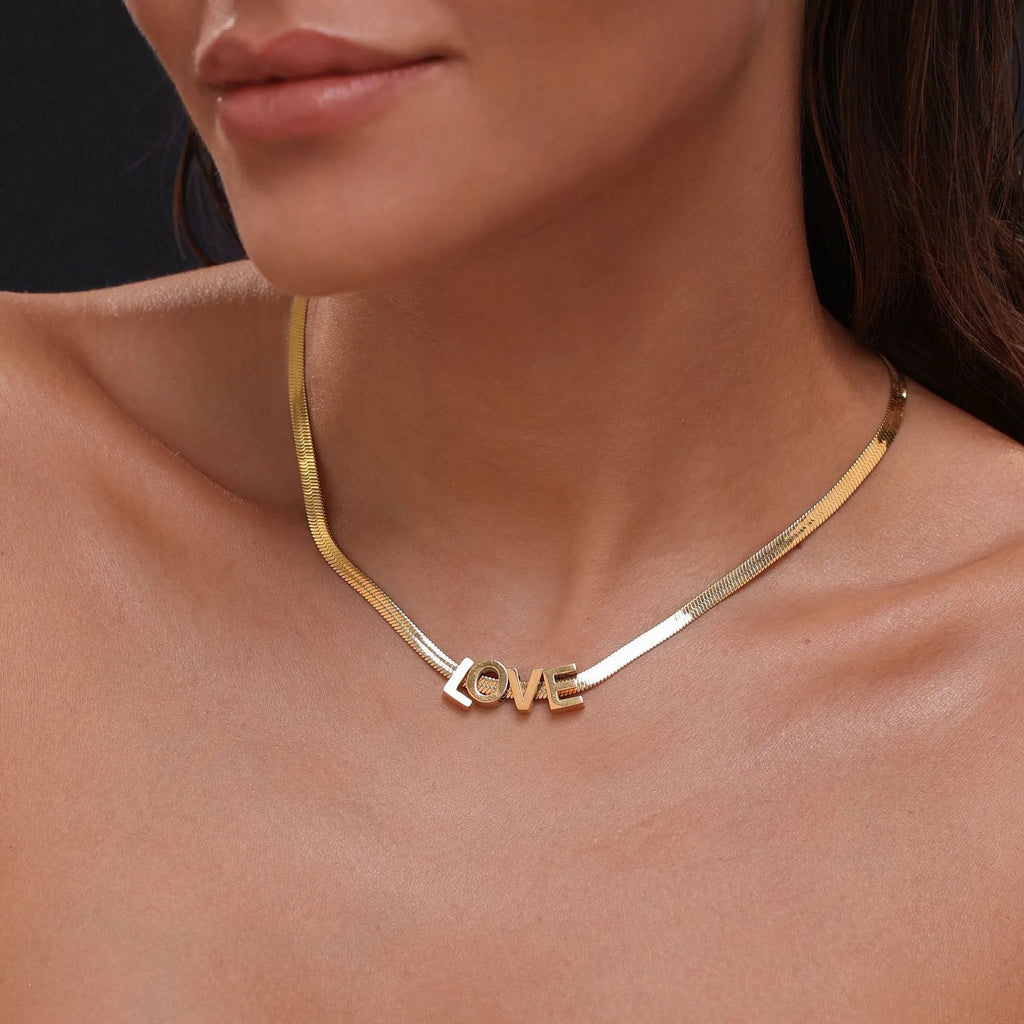 Gold and silver titanium steel necklaces showing letter A, number 7, and love heart charms on a 40.5cm chain.