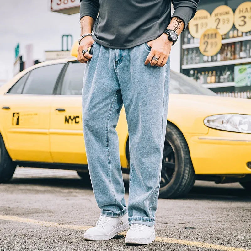 Man wearing dark blue loose straight leg cotton jeans with a mid waist and zipper fly.