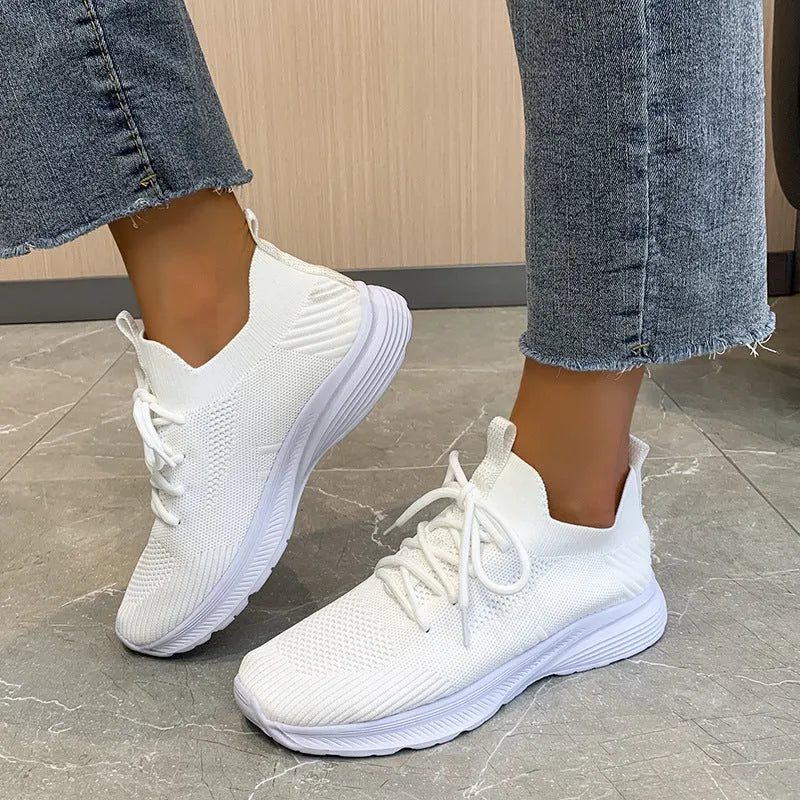 Women's low-top mesh running shoes in creamy white with Flyknit upper and rubber sole.