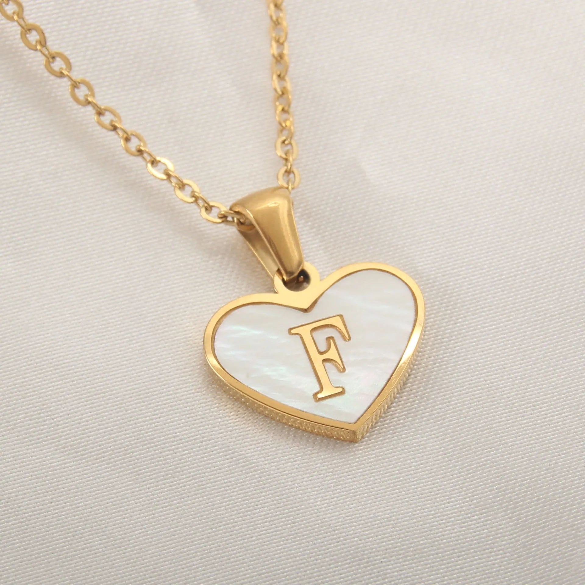 Gold plated heart-shaped necklace with a personalised initial letter and white shell detail on a 50cm adjustable chain.