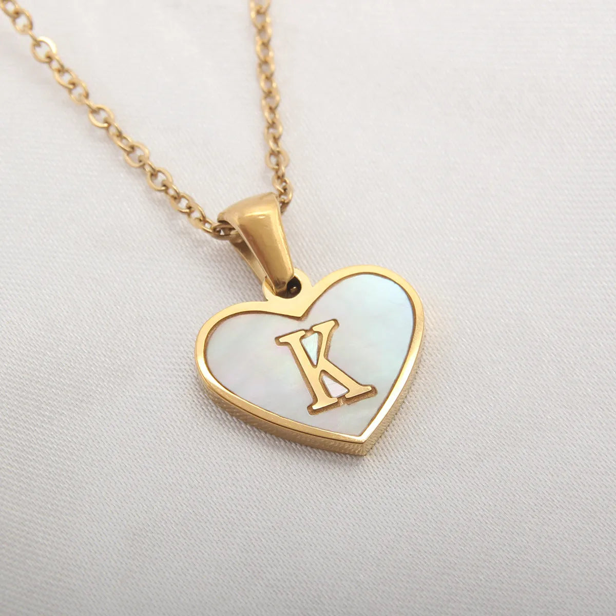 Gold plated heart-shaped necklace with a personalised initial letter and white shell detail on a 50cm adjustable chain.