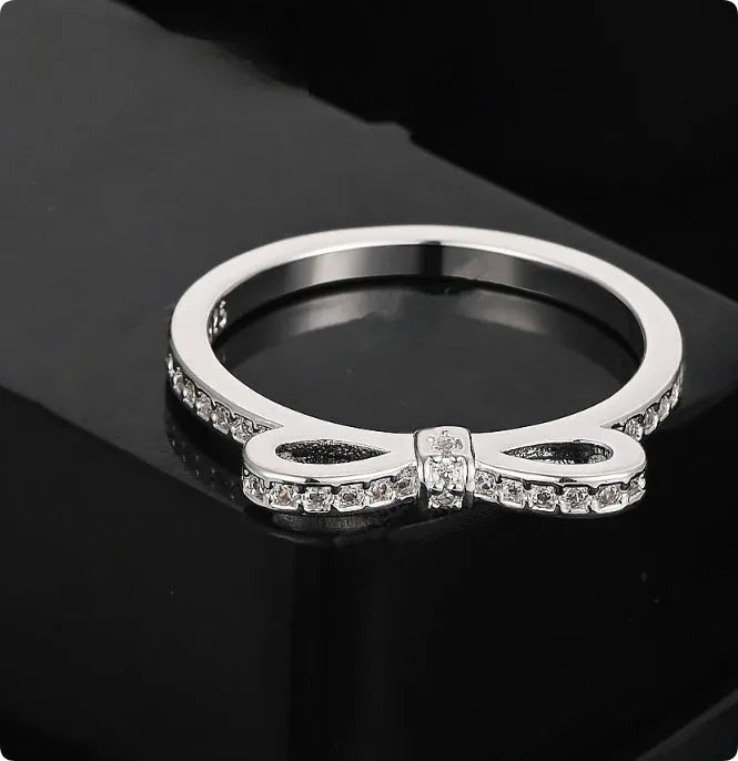 Silver bow-shaped ring with rhinestone detailing, shown in electroplated finish
