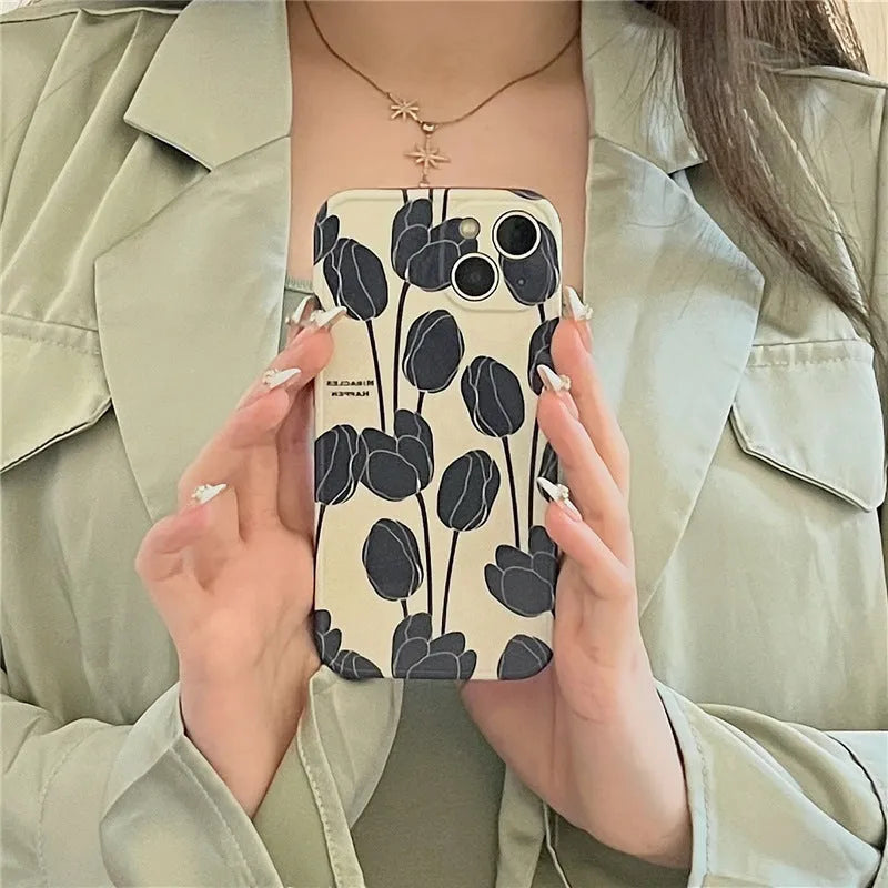 Black silicone iPhone case with a printed white and grey tulip floral design on the back.
