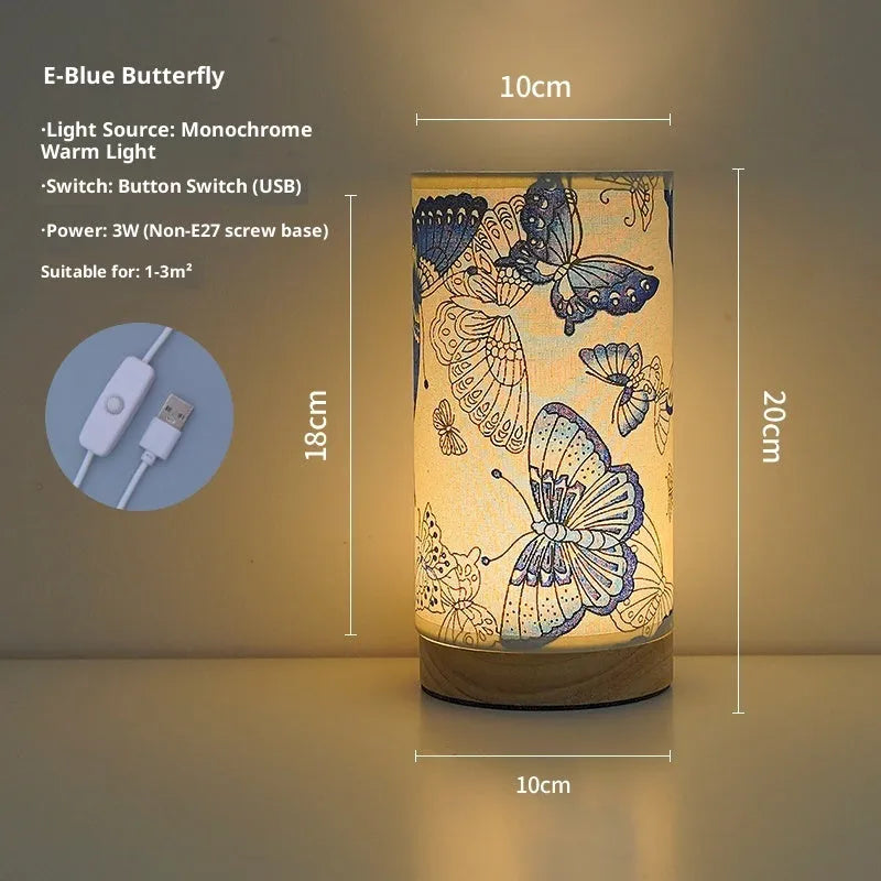 Creative floral fabric table lamp with remote control, warm LED light, black oil painting pattern on a bedside table