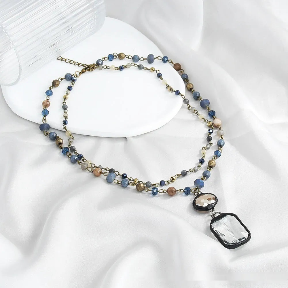 Tribal-style retro necklace with a blue stone and glass pendant on a metal chain.