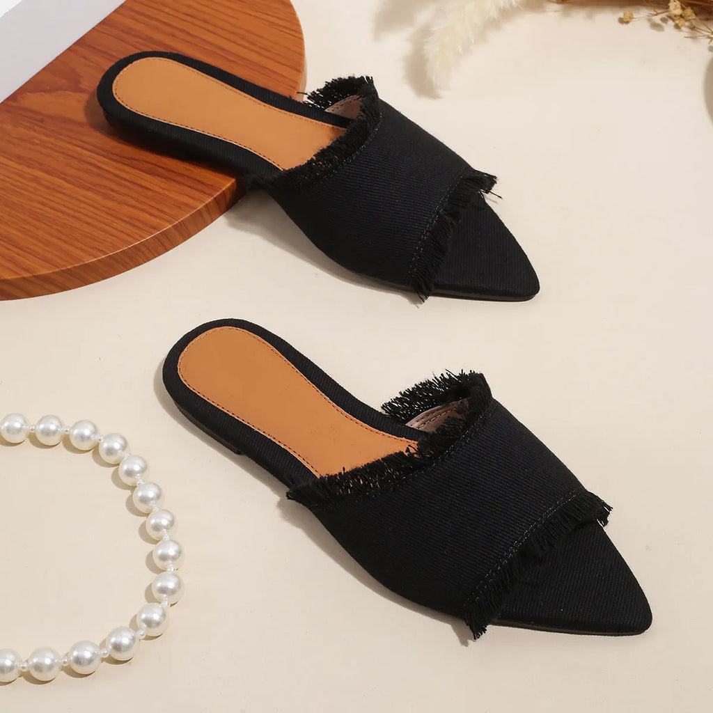 Women's denim flat slipper with leather lining, PVC sole, and a decorative tassel in a solid colour.