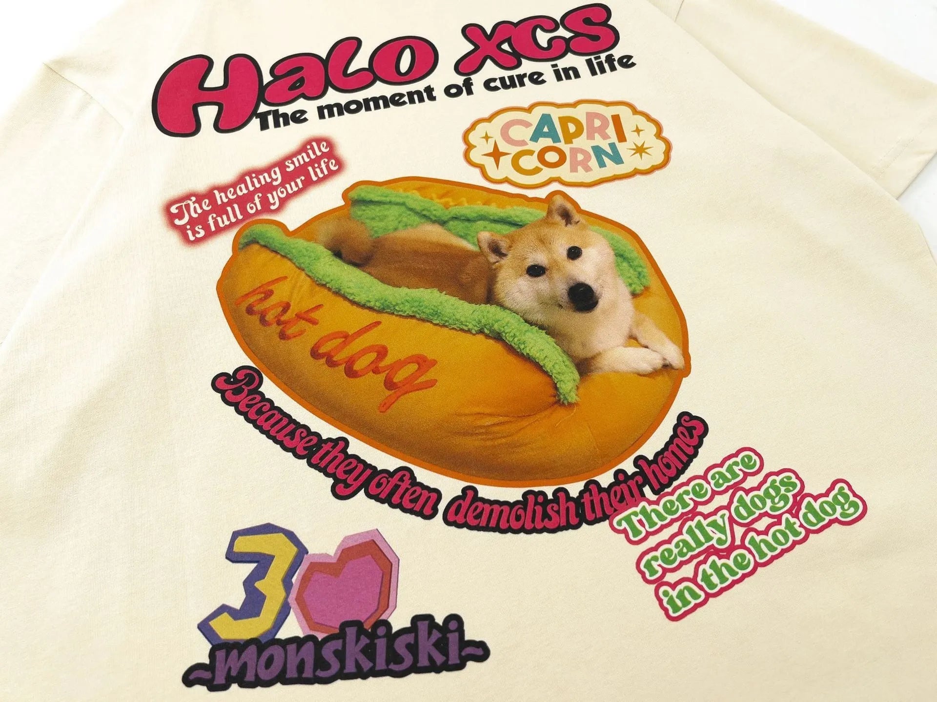White cotton t-shirt with a cartoon print of a hamburger and a dog, showing a round neck and short sleeves.