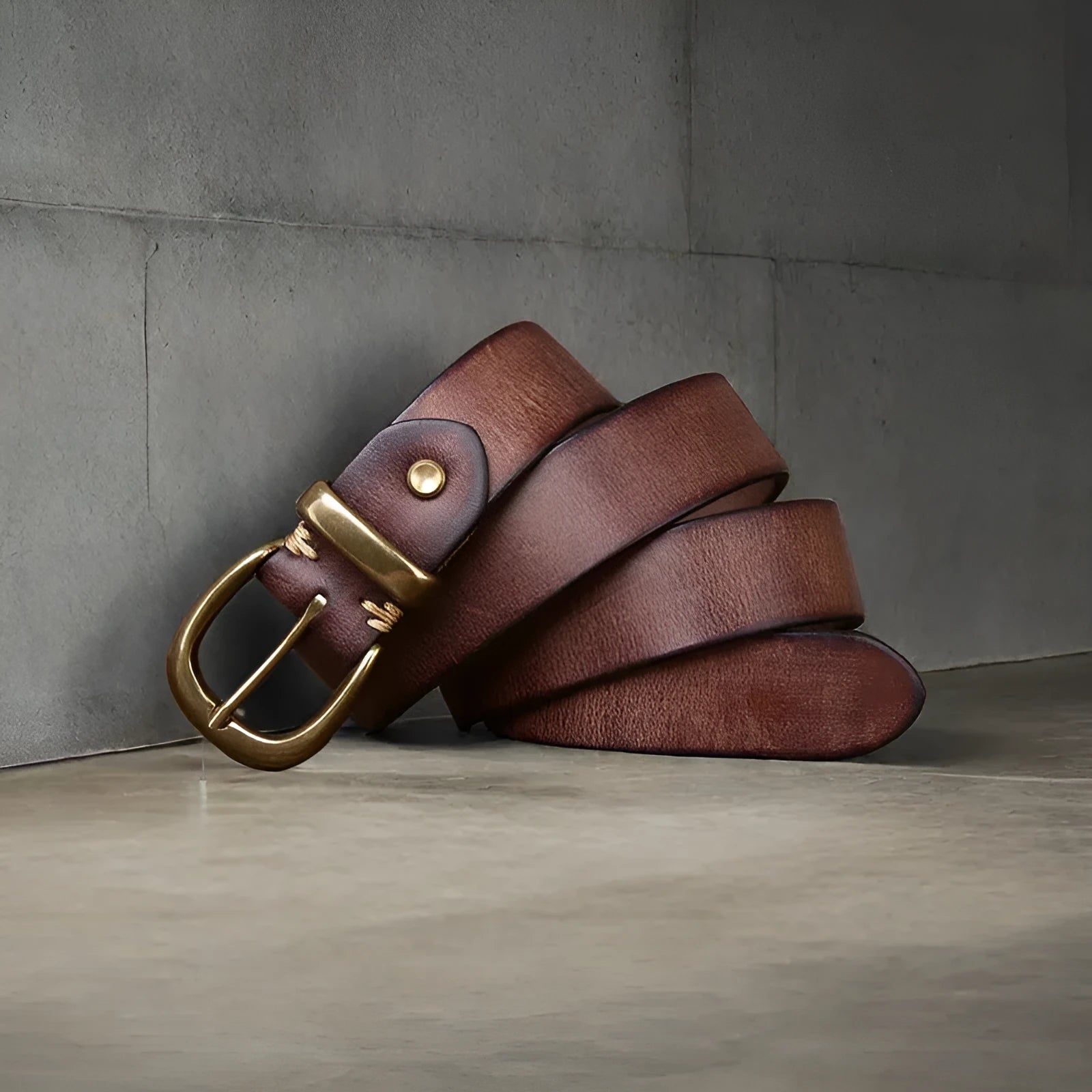 Men's black cattlehide leather belt with a copper pin buckle on a jeans background.