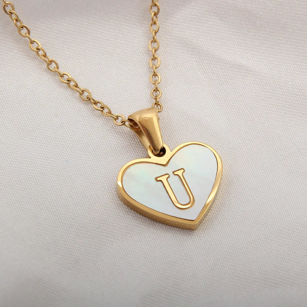 Gold plated heart-shaped necklace with a personalised initial letter and white shell detail on a 50cm adjustable chain.