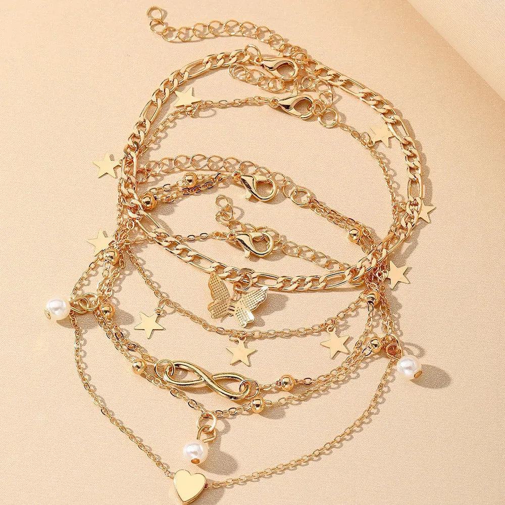 Set of four alloy anklets with butterfly, pearl, and heart designs on a white background.