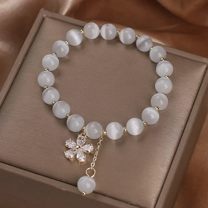 White cat's eye stone women's bracelet with flower tassel and safety buckle.