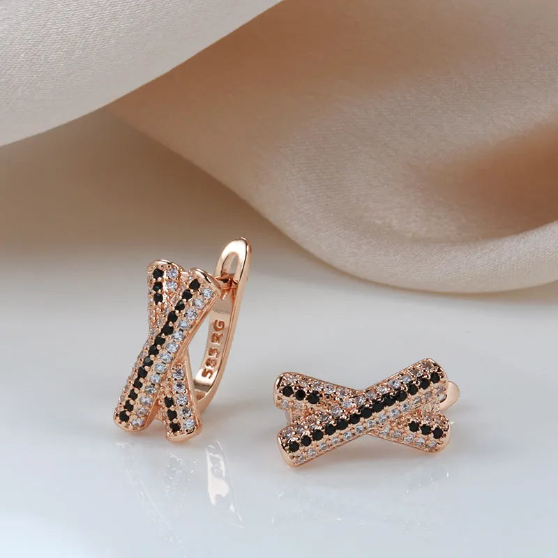 Pair of rose gold copper earrings with hollow-out X-shaped geometric design on light background