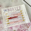 Set of five white plastic retractable ballpoint pens with blue and red nurse-themed humorous text printed on the barrels.
