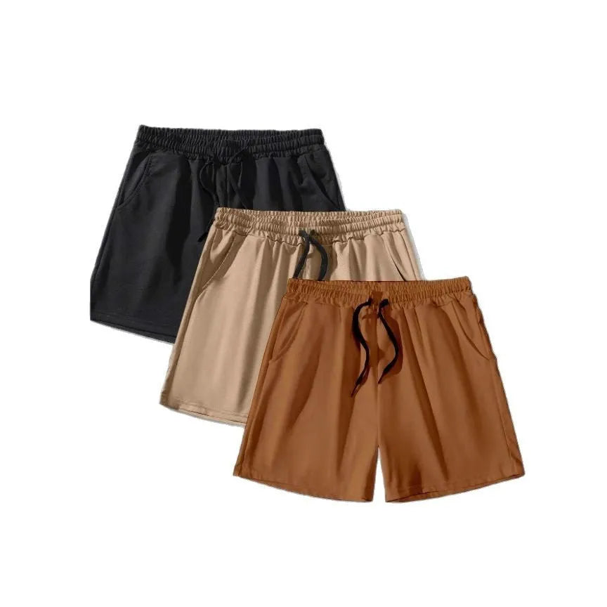 Three pairs of men's solid colour drawstring shorts in black, khaki, and light brown laid flat.