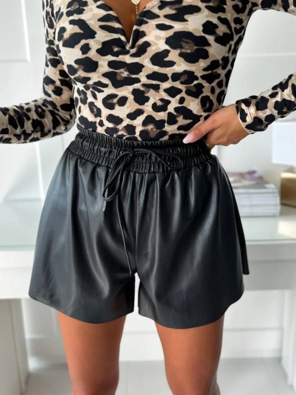 Women's black PU leather wide-leg shorts with a front lace-up drawstring waist detail.