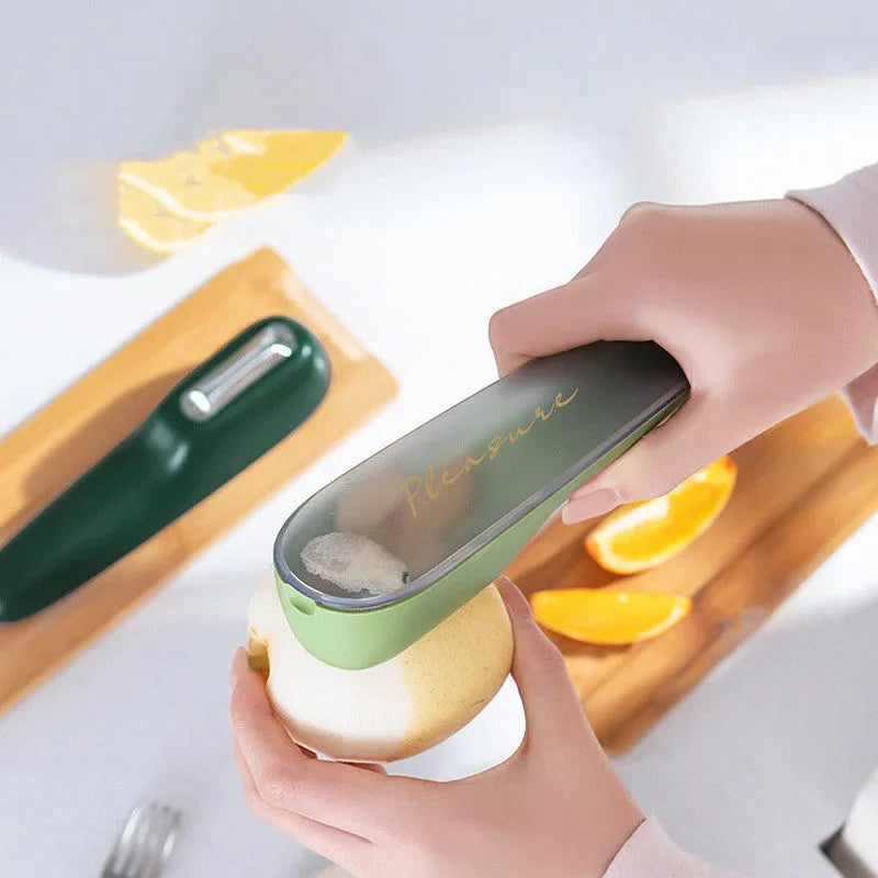 Dark green vegetable peeler with a storage tube and stainless steel blade on a kitchen counter.