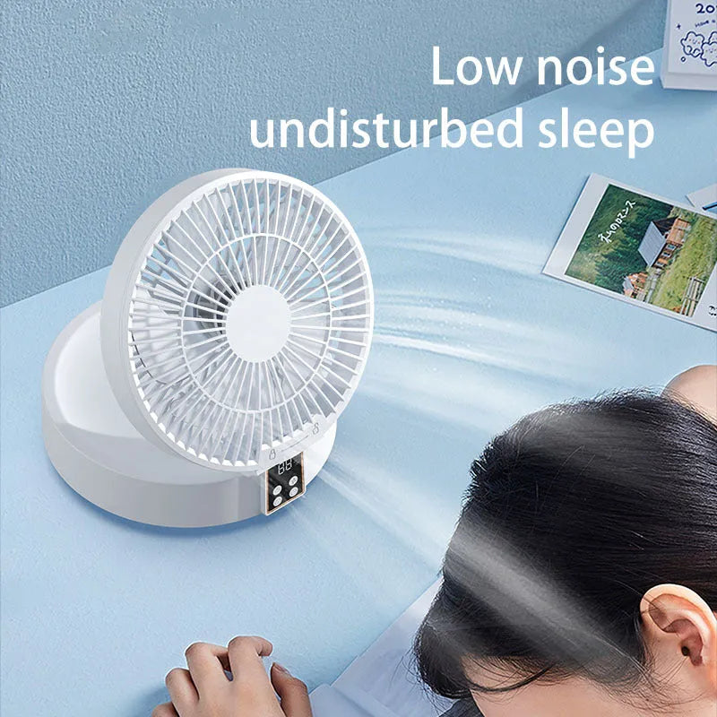 White portable folding fan with remote control on wooden desktop next to USB charging cable