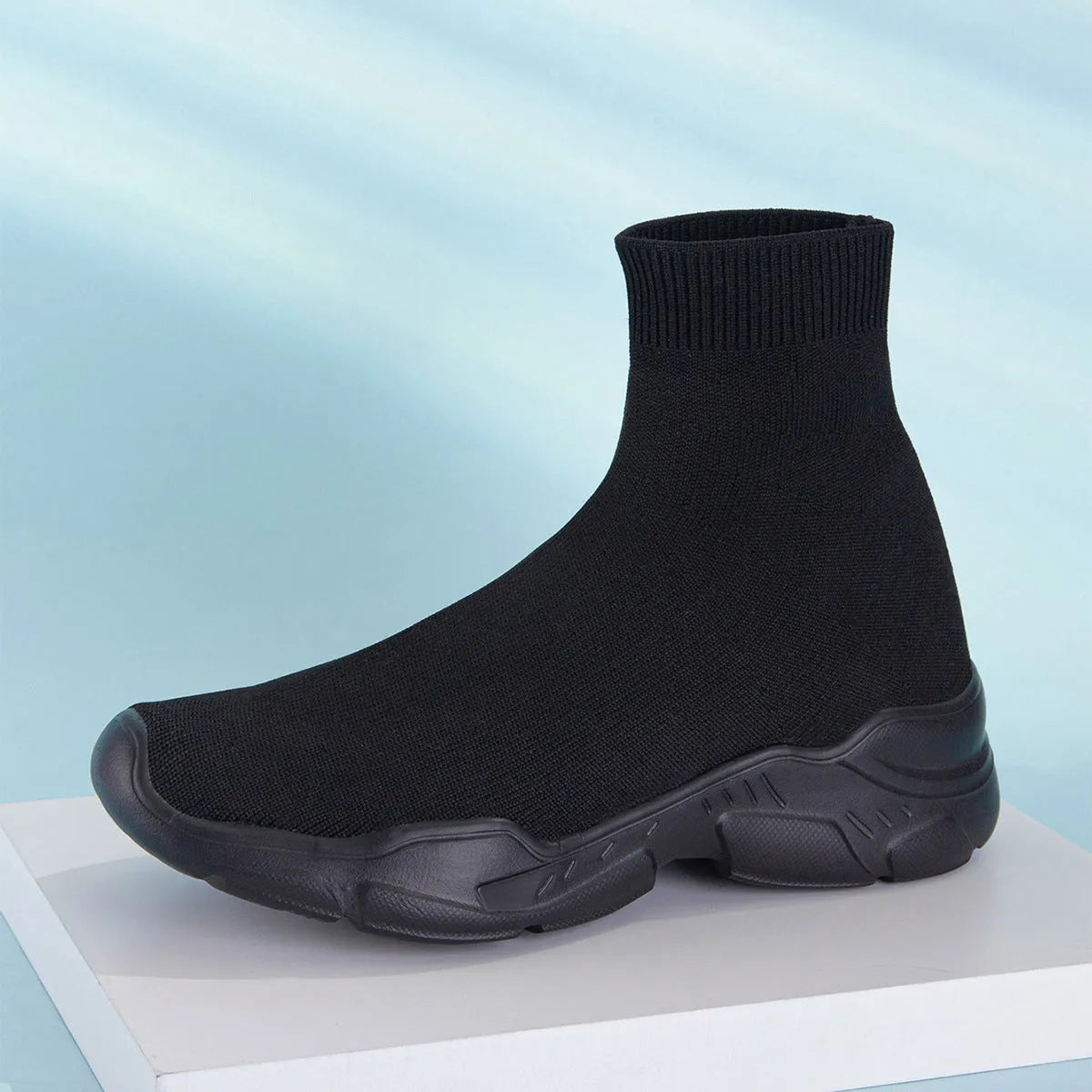 Thick-soled slip-on casual shoes in black with fabric upper, mid-top design, and round toe.