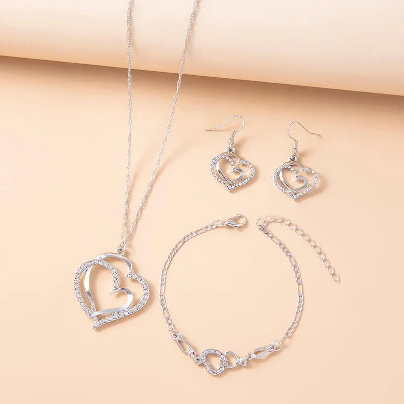 Silver romantic crystal heart jewelry set with bracelet necklace earrings on white background