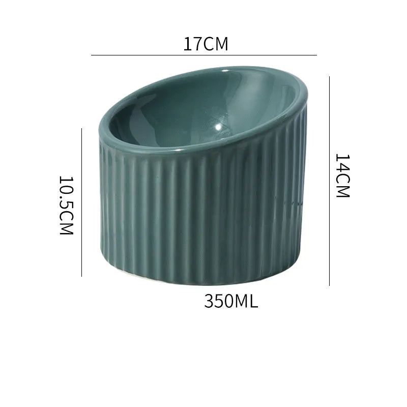 Ceramic elevated cat bowl in light green, showing its tilted, round shape and raised design on a table.