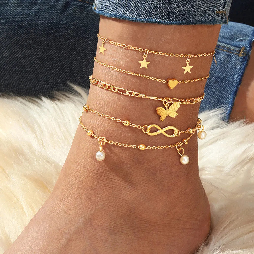 Set of four alloy anklets with butterfly, pearl, and heart designs on a white background.