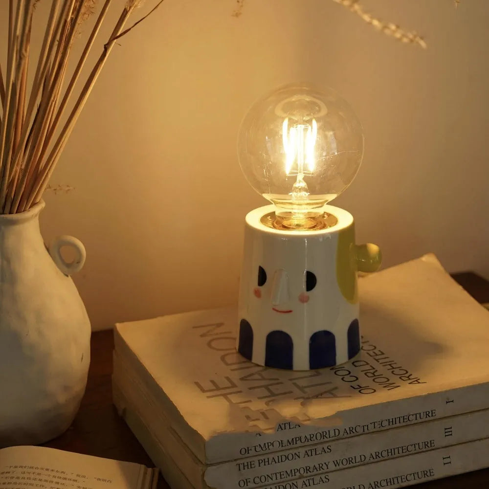 Handmade ceramic bedside lamp with ball headlight colour design on a table.
