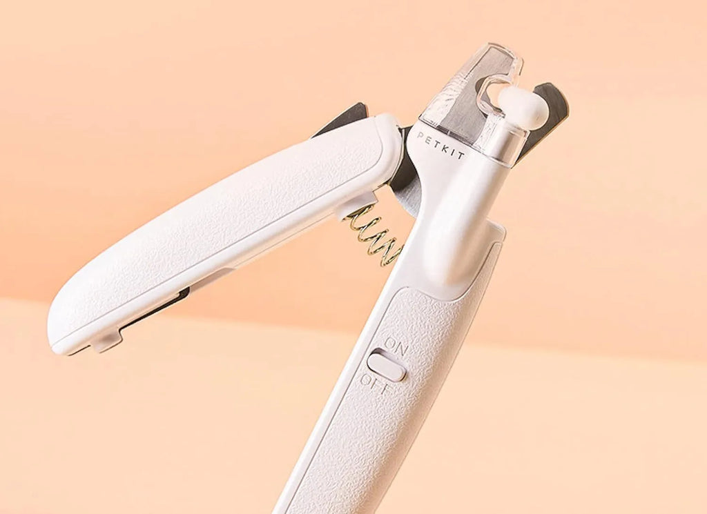 White pet nail clippers with LED light, anti-splash transparent guard, and a leather-like handle on a blue background.