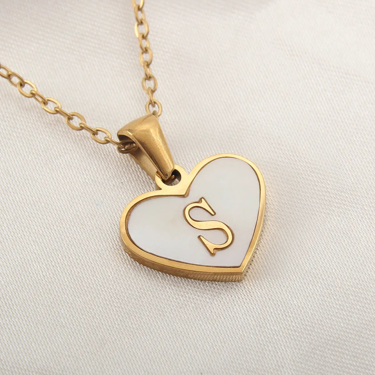 Gold plated heart-shaped necklace with a personalised initial letter and white shell detail on a 50cm adjustable chain.