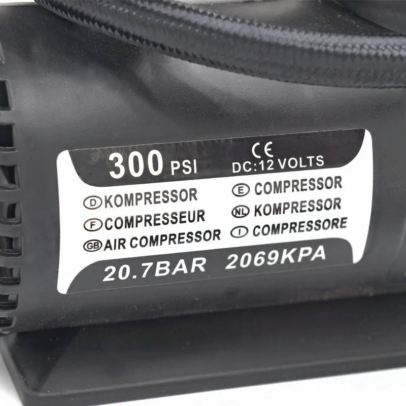 Black 12V portable mini air compressor with 300 psi gauge, 9-foot cord, and two adapter nozzles on a neutral background