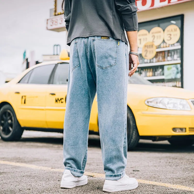 Man wearing dark blue loose straight leg cotton jeans with a mid waist and zipper fly.