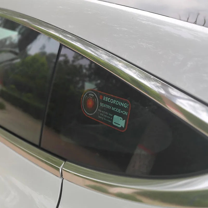 Pair of white electrostatic warning stickers for Tesla Sentry Mode on a car window.