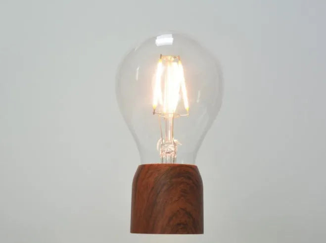 Magnetic levitation floating light bulb hovering above imitation wood base
