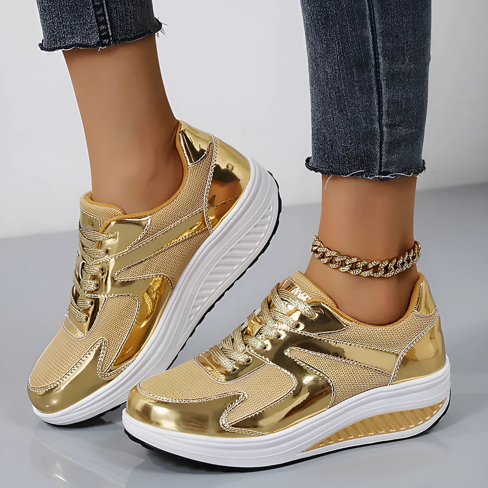 Women's gold platform trainers with mesh upper and cross-strap design showing 3-5cm heel elevation