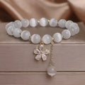 White cat's eye stone women's bracelet with flower tassel and safety buckle.