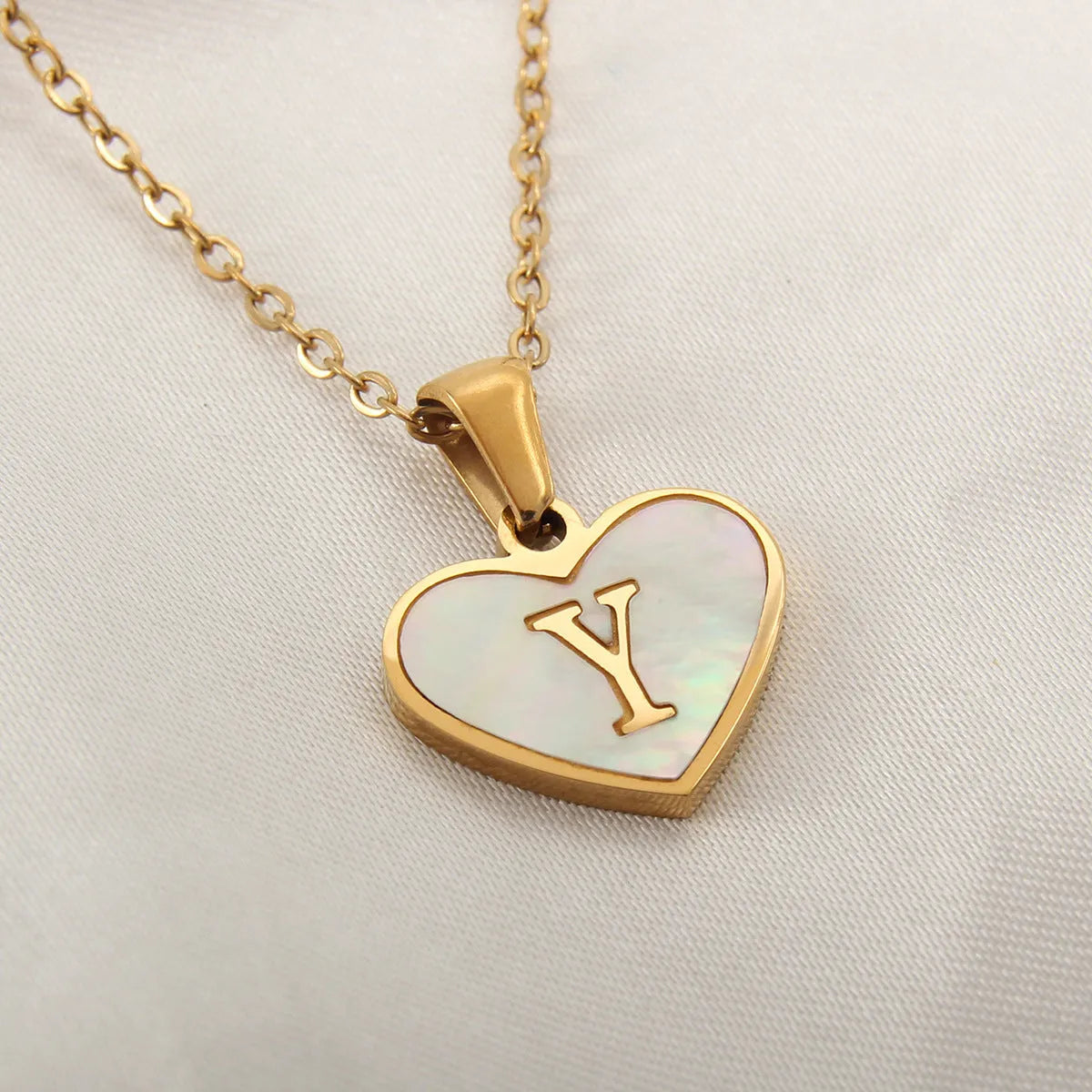 Gold plated heart-shaped necklace with a personalised initial letter and white shell detail on a 50cm adjustable chain.