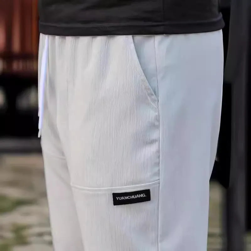 Man wearing lightweight grey polyester trousers, showcasing fit and casual style for spring or autumn.