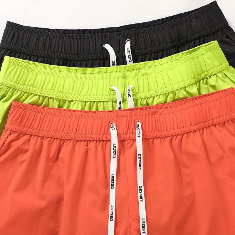 Men's loose-fit polyester surfing pants on a beach, shown in orange red, fluorescent green, and black colour options.