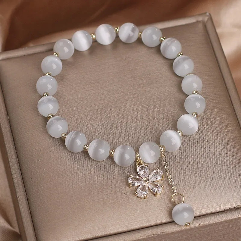 White cat's eye stone women's bracelet with flower tassel and safety buckle.