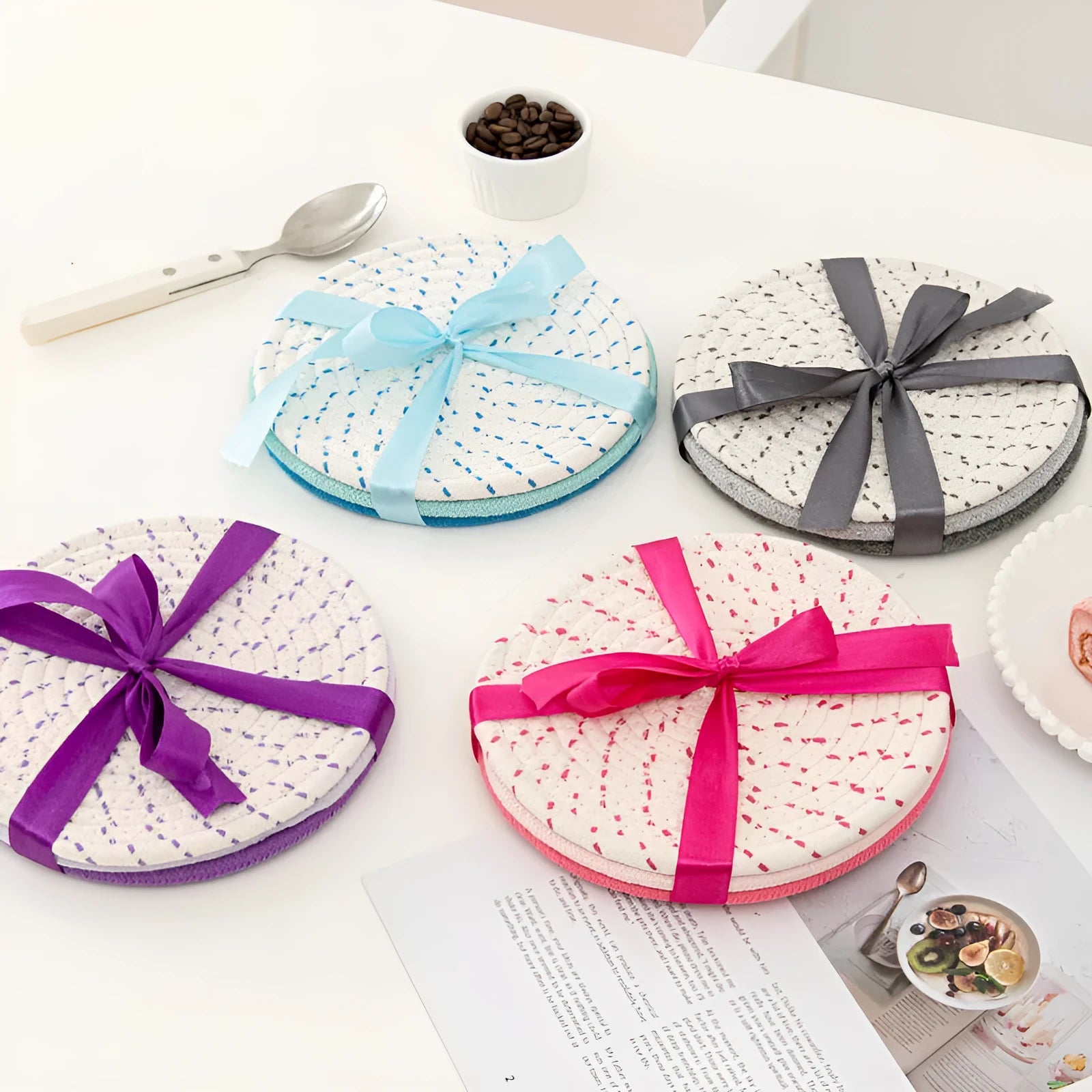 Three round grey cotton cord coasters on a wooden table