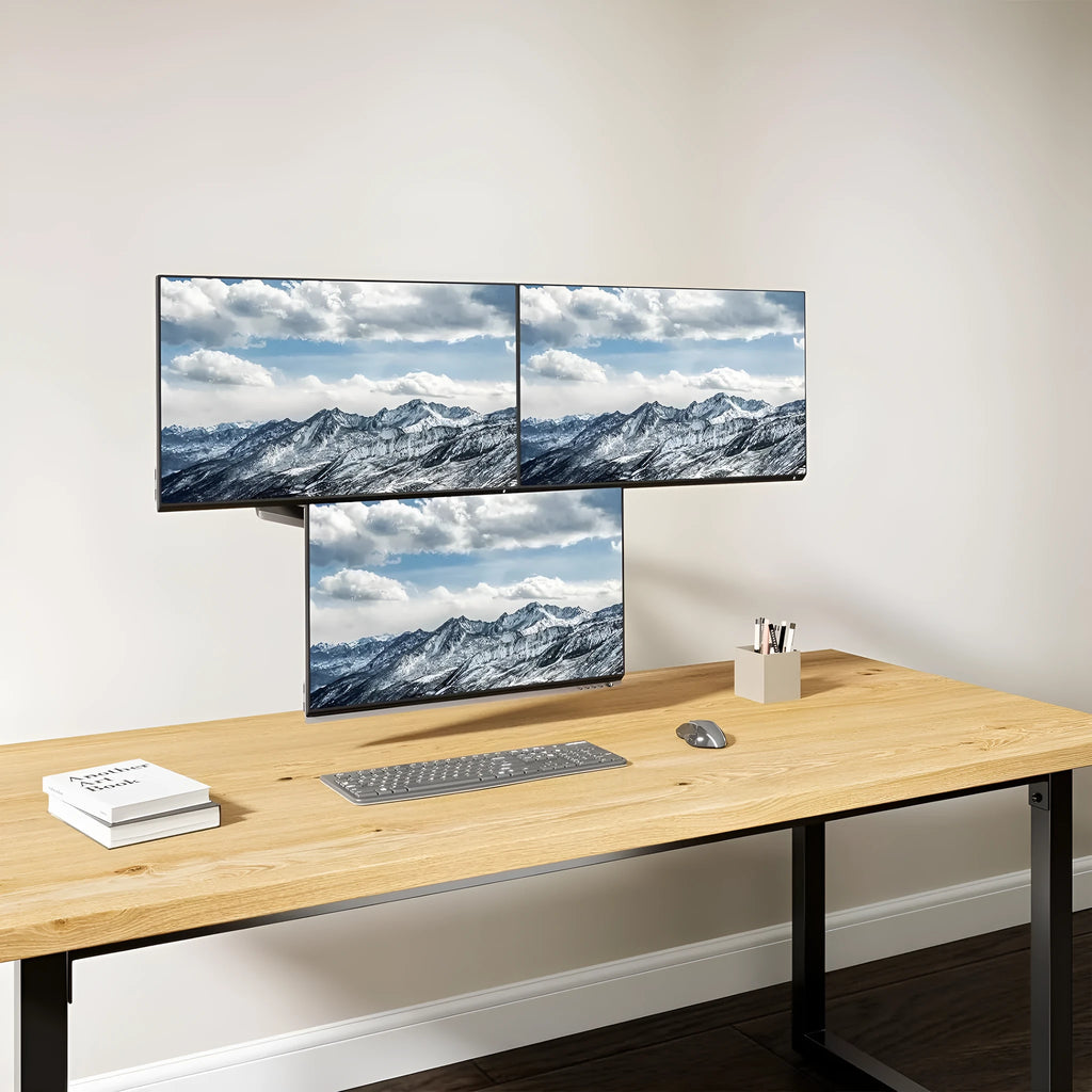 Black three-arm gas spring monitor mount holding a 27-inch screen above a desk.