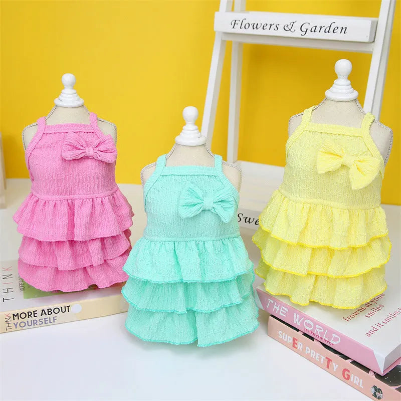 Small dog wearing princess dress with candy-layered skirt in rose red, yellow, or water green colour