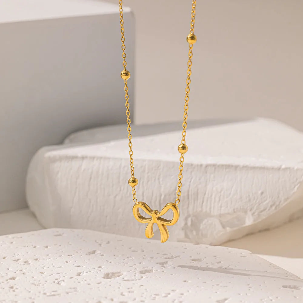 Gold-coloured titanium steel necklace with bow design and cross chain construction