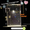 DIY snowy night light kit showing assembled snowflake street lamp scene with warm LED glow on a desktop.