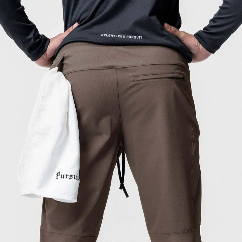 Man wearing dark grey loose-fit ankle-tied polyester running trousers for fitness.