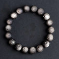 Natural obsidian crater ball bracelet in gold or silver finish on a wrist, showing textured bead detail.