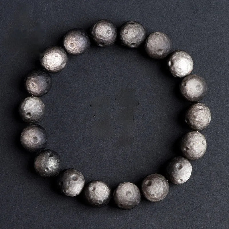Natural obsidian crater ball bracelet in gold or silver finish on a wrist, showing textured bead detail.