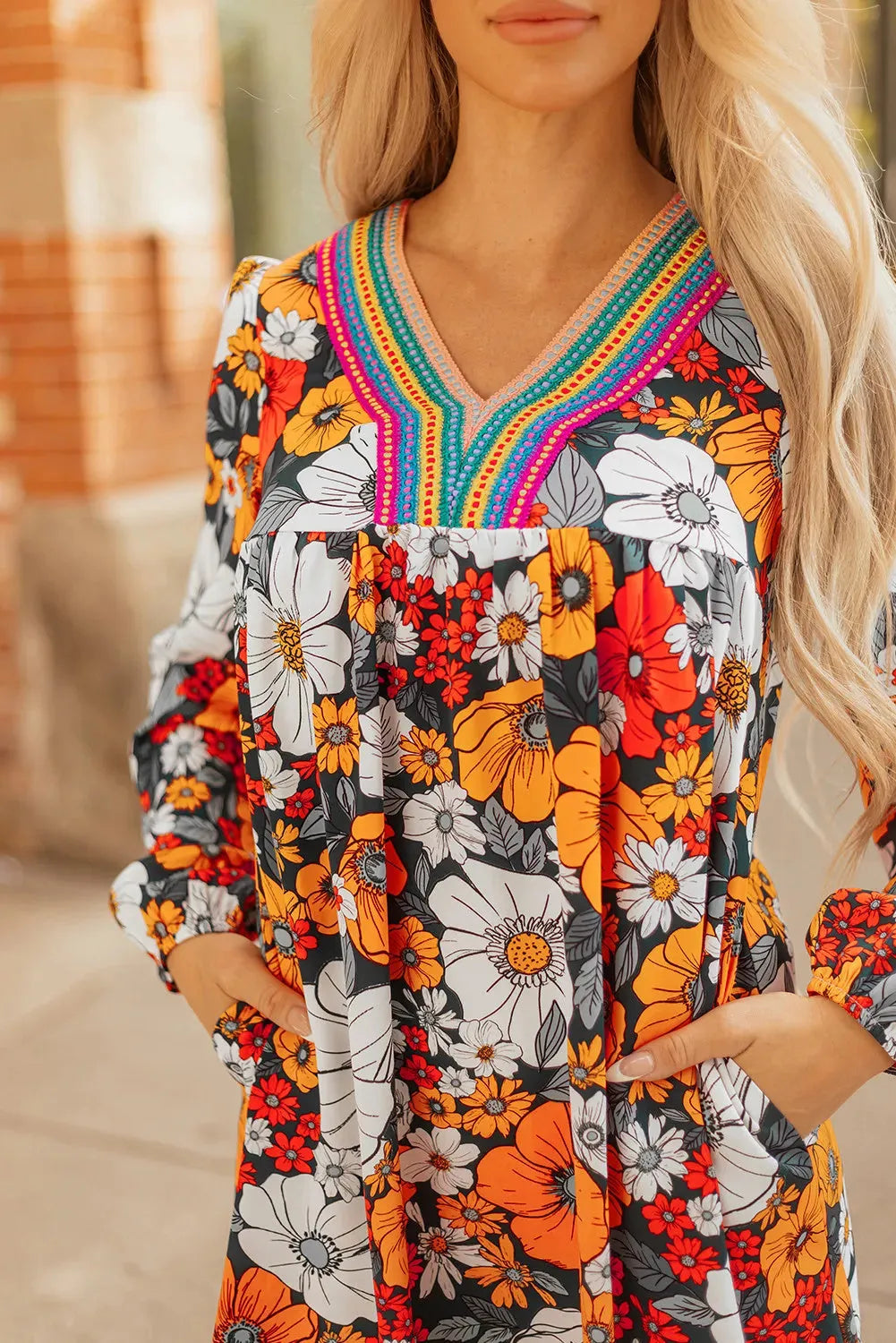 Orange floral print and striped lace V-neck long sleeve mini dress on a hanger.